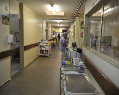 Enfermeira anda em corredor de hospital.
