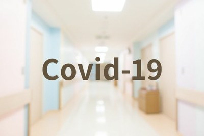 Foto de corredor de hospital desfocado com a palavras COVID 19 em marrom.