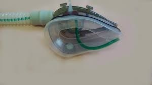 #Pracegover Fotografia de máscara Spirandi, composta por um bocal, semelhante a de um aparelho de nebulização e uma mangueira de oxigênio