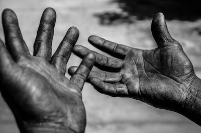 Foto mostra duas mãos sujas com as palmas das mãos para cima