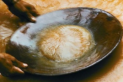 #Paratodosverem: Imagem mostra mãos de garimpeiro segurando uma peneira sobre uma superfície de água, realizando a mineração de ouro