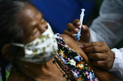 #Paratodosverem: Imagem mostra senhora indígena protegida por máscara recebendo dose de vacina no braço esquerdo