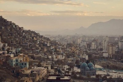Imagem da cidade de Cabul, no Afeganistão. À esquerda vê-se um morro com muitas casas, ao centro uma mesquita e muitos prédios. Ao fundo uma montanha.
