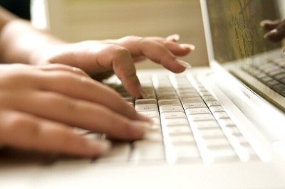Foto de duas mãos digitando em um teclado de computador